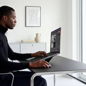 AMP11116 - Slim Fold Laptop Stand | LD201-S7 showing side view of person using MacBook laptop propped up on laptop stand and using mouse