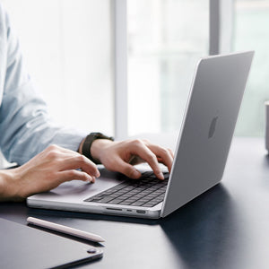 Spigen MacBook Pro 14-inch Air Skin in Frost Clear showing a person typing on a MacBook with the Frost Clear case applied, placed on a desk in an office setting